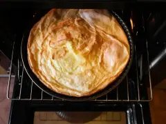 Puszysty sernik piecze się w piekarniku z termoobiegiem, nabierając złotego koloru.