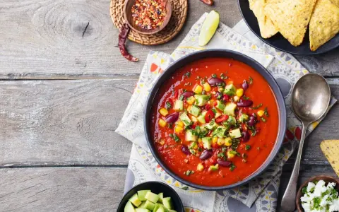 Prawdziwa zupa meksykańska z fasolą, kukurydzą i awokado, podana z nachos i serem.