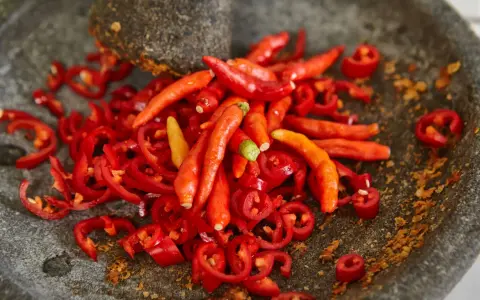 Ostry jak diabli! Całe mnóstwo czerwonych papryczek chili, niektóre pokrojone w plasterki, leżą w kamiennym moździerzu. To zapowiada najostrzejszą paprykę!