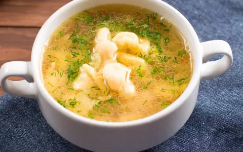 Aromaticzna zupa zacierkowa z koperkiem, podana w białej miseczce na granatowym obrusie.