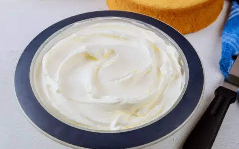 Puszysta bita śmietana z mascarpone w misce, gotowa do dekorowania biszkoptów.
