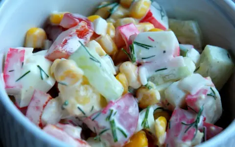 Pyszna, kremowa sałatka z surimi, kukurydzą, ogórkiem i jajkiem, posypana świeżym koperkiem. Idealna na każdą okazję, to najlepsza sałatka z surimi!