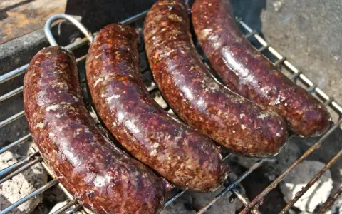 Cztery soczyste kaszanki na grilla, rumieniące się nad żarem. Idealne na letnie spotkanie.