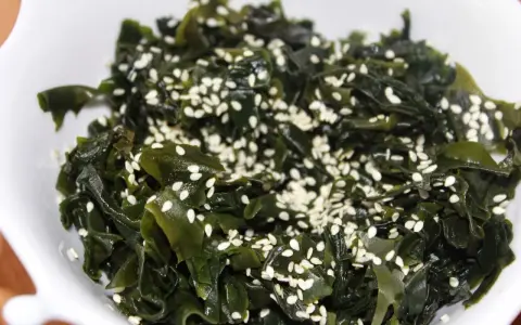 Sałatka z wodorostów wakame, posypana sezamem. To pyszne i zdrowe danie, które warto spróbować, jeśli zastanawiasz się, wakame co to.