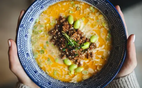 Miseczka tantanmen z mielonym mięsem, edamame i szczypiorkiem.