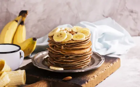 Stos naleśników z plasterkami banana i orzechami. Idealny pomysł, co zrobić z bananów na pyszne śniadanie.