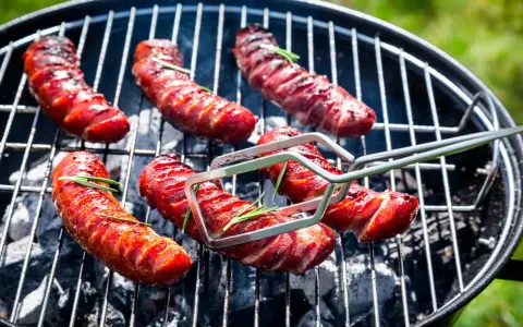 Soczysta kiełbasa na grilla, rumieniąca się nad żarem. Aromatyczny rozmaryn dodaje jej wyjątkowego smaku.