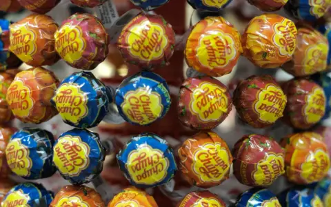 Zbliżenie na kolorowe lizaki Chupa Chups w opakowaniach z owocowymi wzorami.