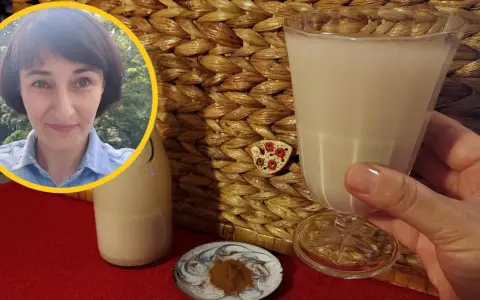 Kobieta z uśmiechem prezentuje szklankę z wodą owsianą, obok butelka i cynamon.