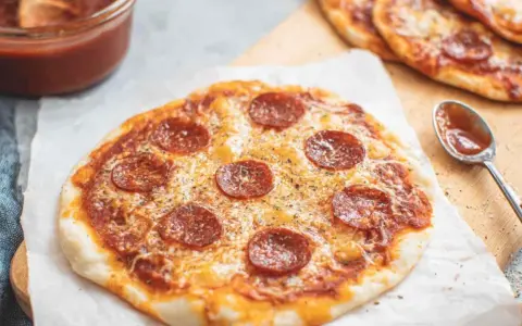 Pyszna pizza z tortilli na patelni, z serem i pepperoni, gotowa do podania. Obok sos i łyżeczka.
