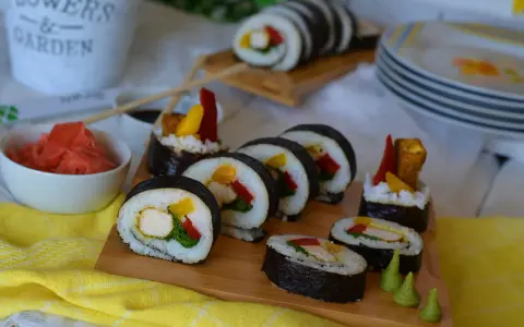 Pyszne sushi z kurczakiem, papryką i mango. Podane na desce z dodatkami: marynowanym imbirem i wasabi.