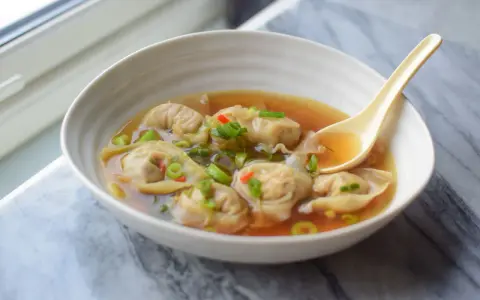 Aksamitna zupa wonton z kawałkami chili i szczypiorku, gotowa do nabrania łyżką.