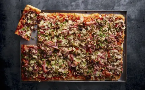 Najlepsza pizza domowa na dużą blachę, obficie posypana pieczarkami, szynką i oliwkami. Idealna na rodzinne spotkanie.