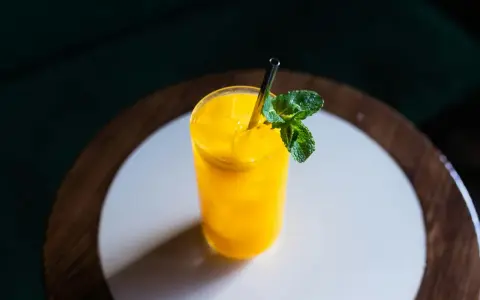 Orzeźwiający koktajl z mango, z lodem i listkami mięty, podany w szklance ze słomką.