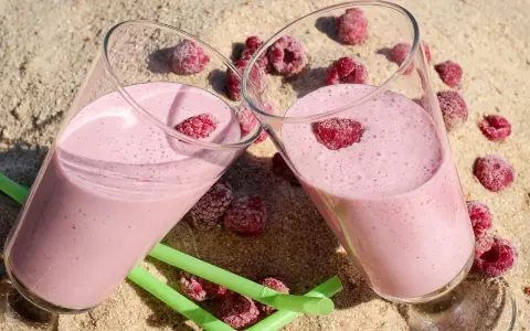 Dwa pyszne malinowe smoothie na piasku, idealne na lato. Inspiracja na zdrowe smoothie przepisy.