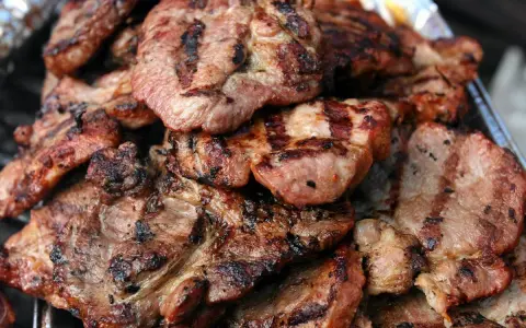 Soczysta karkówka z grilla, idealna po marynacie. Grillowane plastry mięsa z charakterystycznymi paskami.