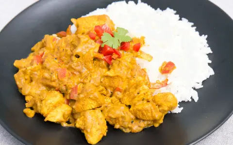 Kurczak w sosie curry z ryżem, posypany papryką i kolendrą. Prosty przepis na pyszny obiad.