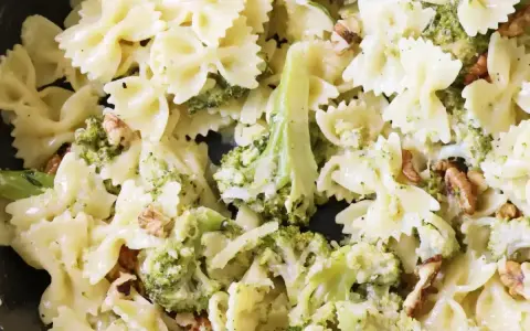 Pyszny makaron farfalle z brokułami w kremowym sosie śmietanowym, posypany orzechami włoskimi.