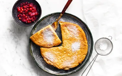 Puszysty omlet z air fryera, posypany cukrem pudrem, podany z żurawiną. Idealny na śniadanie.