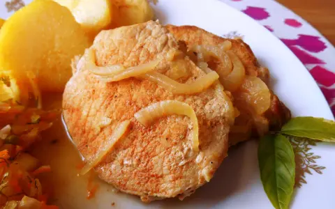 Pyszny schab w cebuli, idealny na niedzielny obiad, podany z ziemniakami i surówką.