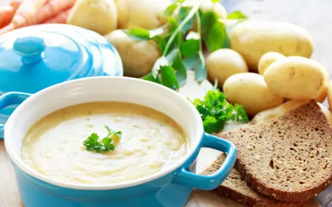 Aksamitna zupa ziemniaczana, przepis babci, z chlebem i świeżymi ziemniakami w tle.
