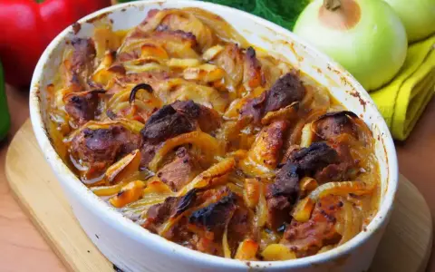 Pyszne danie z łopatki na szybko, zapiekane z cebulą w białym naczyniu. Obok papryka, cebule i koperek.