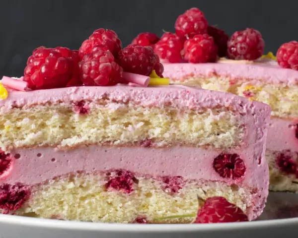 Pyszny tort z warstwami biszkoptu, przełożony kremem malinowym z mascarpone i świeżymi malinami.