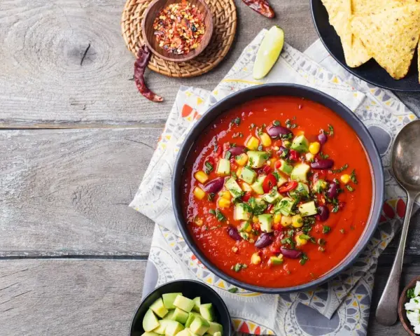 Prawdziwa zupa meksykańska z fasolą, kukurydzą i awokado, podana z nachos i serem.