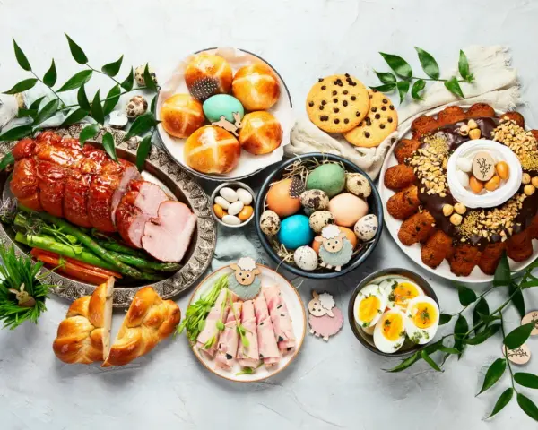 Wielkanocny stół ugina się od pyszności: pieczona szynka, pascha, jajka, bułeczki i inne ciepłe dania na wielkanoc.