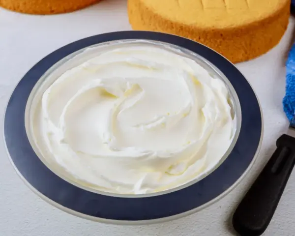Puszysta bita śmietana z mascarpone w misce, gotowa do dekorowania biszkoptów.