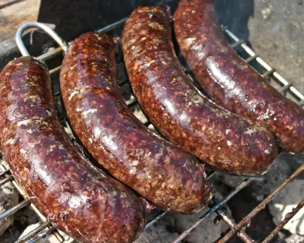 Cztery soczyste kaszanki na grilla, rumieniące się nad żarem. Idealne na letnie spotkanie.