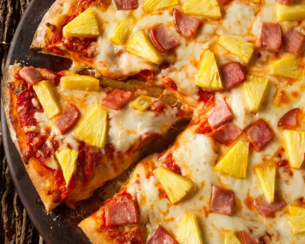 Pyszna pizza z ananasem i szynką, z ciągnącym się serem i chrupiącym ciastem. Idealna na szybki obiad.