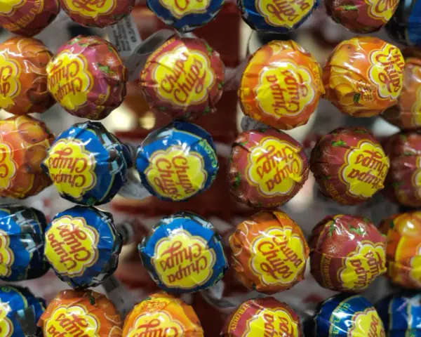 Zbliżenie na kolorowe lizaki Chupa Chups w opakowaniach z owocowymi wzorami.