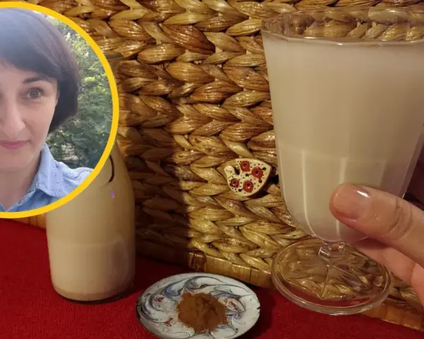 Kobieta z uśmiechem prezentuje szklankę z wodą owsianą, obok butelka i cynamon.