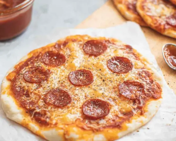 Pyszna pizza z tortilli na patelni, z serem i pepperoni, gotowa do podania. Obok sos i łyżeczka.