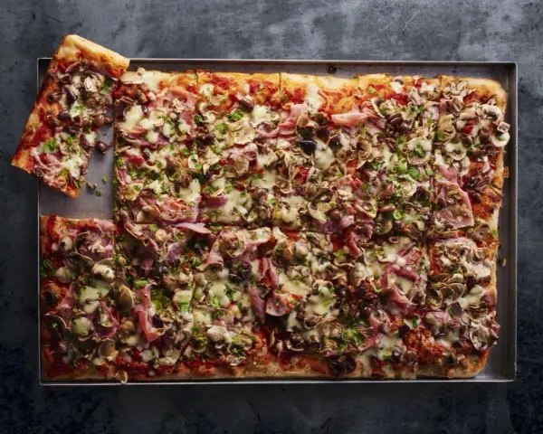 Najlepsza pizza domowa na dużą blachę, obficie posypana pieczarkami, szynką i oliwkami. Idealna na rodzinne spotkanie.