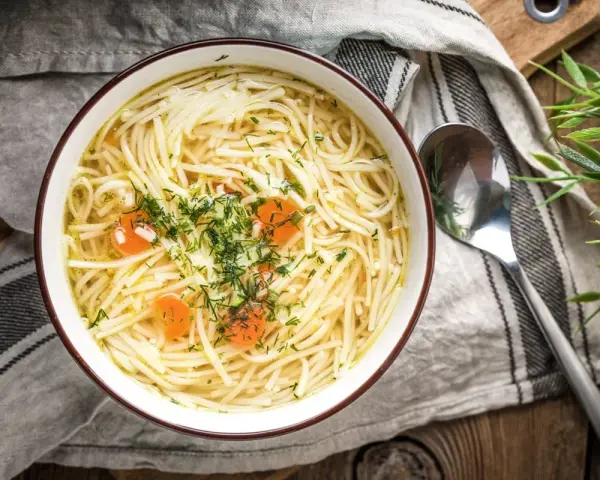 Miseczka domowego rosołu z makaronem i marchewką, posypana koperkiem. Idealny na lekki posiłek, niskokaloryczny rosół kcal.