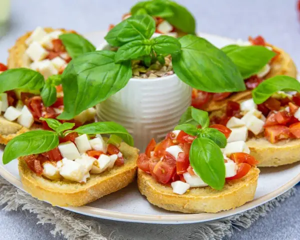 Bruschetta z pomidorami i mozzarellą, świeża bazylia i chrupiące pieczywo. Idealny przepis na letnią przekąskę.
