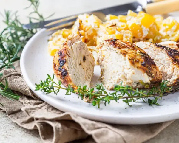 Soczysty indyk z airfryer, pokrojony w plastry, podany z ziemniakami i ziołami.