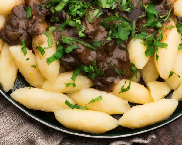 Kopytka z gulaszem, jak u babci! Pyszne ciasto na kopytka przepis babci, polane aromatycznym sosem i posypane natką pietruszki.