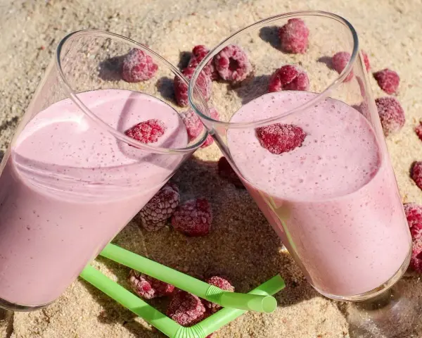 Dwa pyszne malinowe smoothie na piasku, idealne na lato. Inspiracja na zdrowe smoothie przepisy.