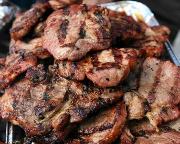 Soczysta karkówka z grilla, idealna po marynacie. Grillowane plastry mięsa z charakterystycznymi paskami.