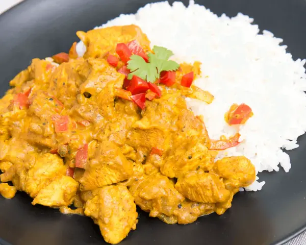 Kurczak w sosie curry z ryżem, posypany papryką i kolendrą. Prosty przepis na pyszny obiad.