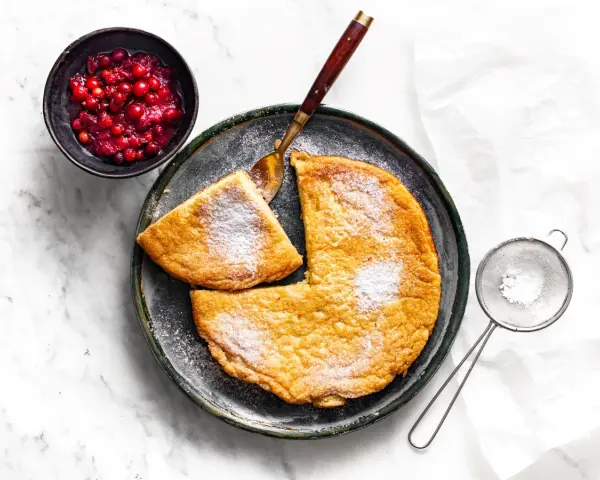 Puszysty omlet z air fryera, posypany cukrem pudrem, podany z żurawiną. Idealny na śniadanie.