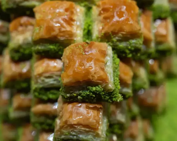 Słodka baklava, co to za przysmak? Warstwy ciasta filo, orzechów i syropu, posypane zielonymi pistacjami.