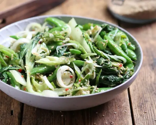 Sałatka z pak choi, groszku cukrowego i cebuli dymki, posypana sezamem. Idealna do dań kuchni azjatyckiej, świetne przepisy na kapustę pak choi.