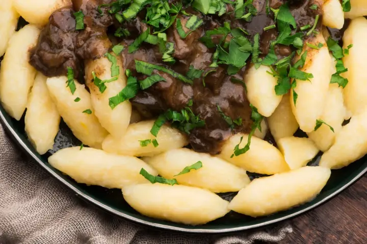 Kopytka z gulaszem, jak u babci! Pyszne ciasto na kopytka przepis babci, polane aromatycznym sosem i posypane natką pietruszki.