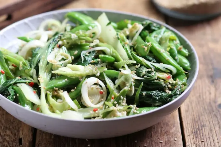 Sałatka z pak choi, groszku cukrowego i cebuli dymki, posypana sezamem. Idealna do dań kuchni azjatyckiej, świetne przepisy na kapustę pak choi.