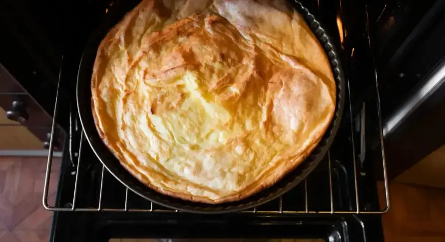 Puszysty sernik piecze się w piekarniku z termoobiegiem, nabierając złotego koloru.