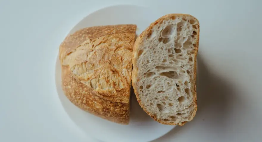 Chleb na talerzu, przekrojony na pół. Idealny przepis na szybki chleb, z chrupiącą skórką i puszystym wnętrzem.